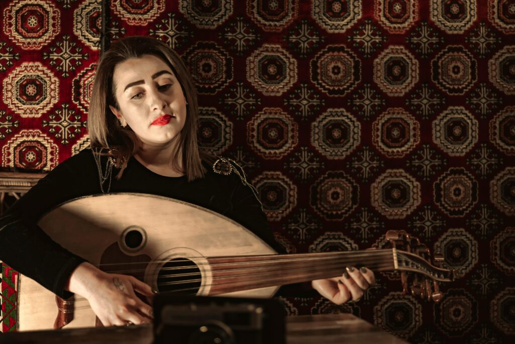 A young woman plays the oud in a traditional setting with patterned textiles. Middle Eastern music scene.